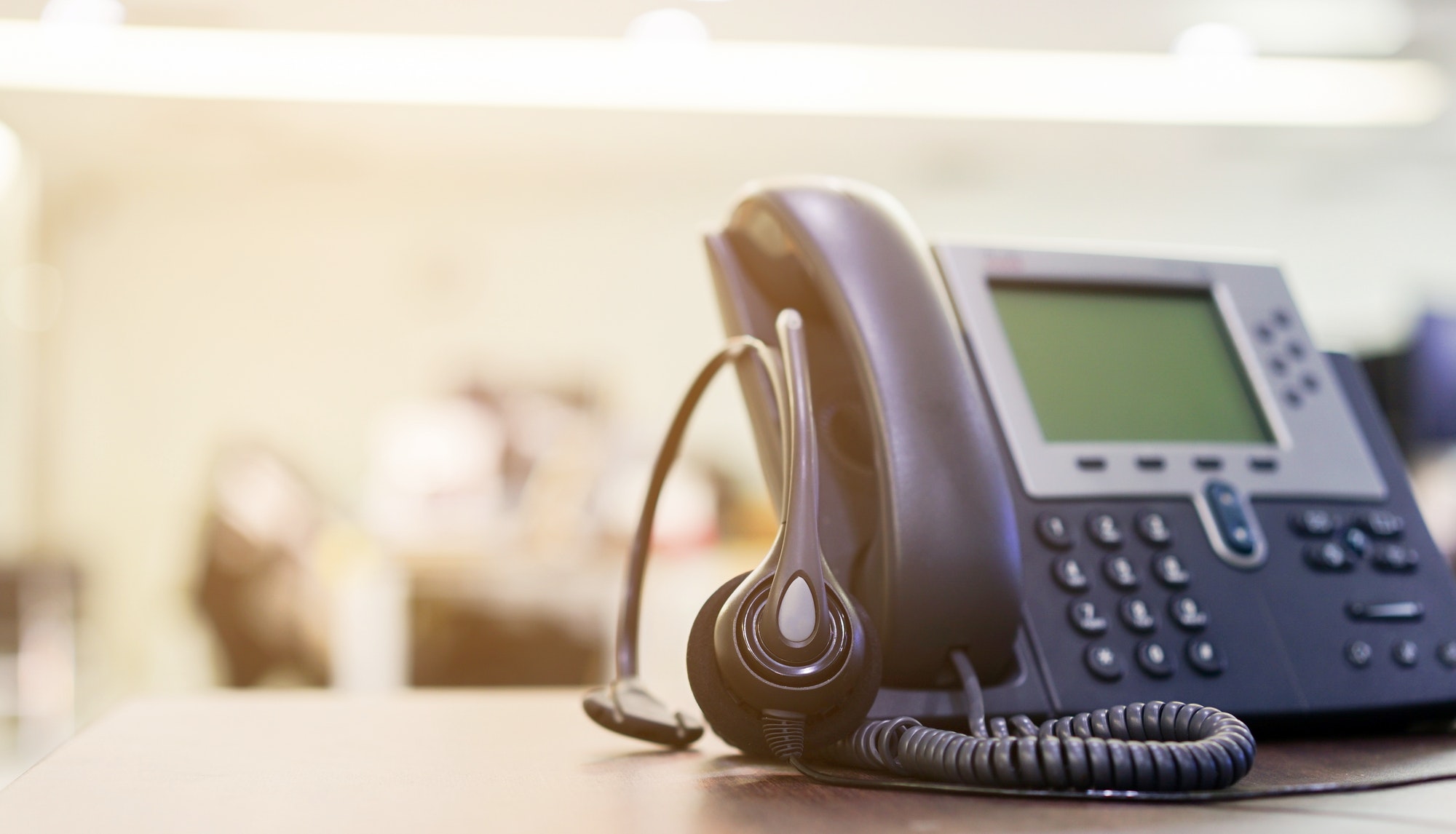 close up on headset devices of call center career with telephone (voip) on table of helpdesk agency