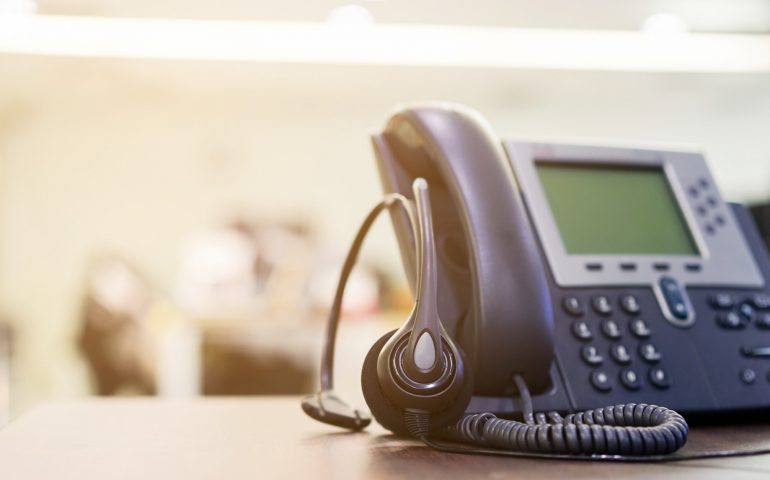 close up on headset devices of call center career with telephone (voip) on table of helpdesk agency